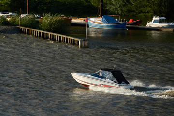 White speed boat goes past a small boat station