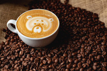 Cappuccino with a pattern on the background of coffee beans