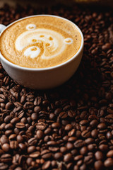 Cappuccino with a pattern on the background of coffee beans