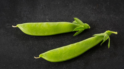 Freshly picked snow peas on a black background.