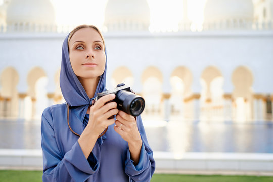Traveling by Unated Arabic Emirates. Woman in traditional abaya standing near the Sheikh Zayed Grand Mosque, famous Abu Dhabi sightseeing.