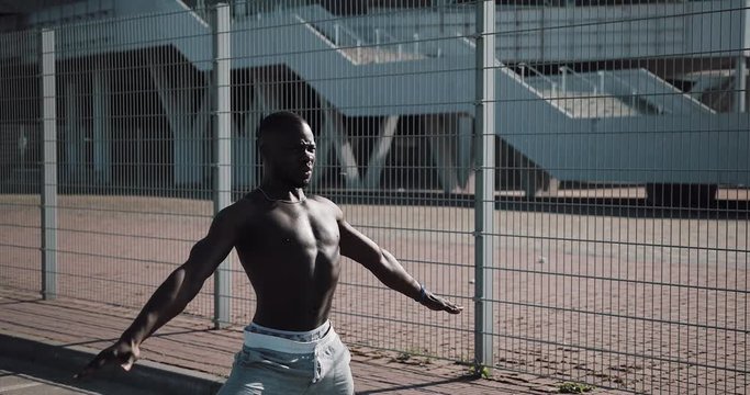 African American male athlet does morning exercise outdoors close up slow motion sun shine. Workout standing on the street near sports stadium. Healthy lifestyle will power motivation concept