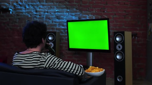 Young brunette man watching a green screen TV