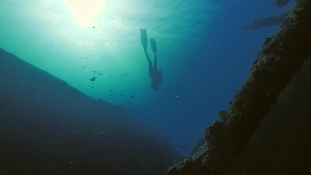 Freediver man cruising inside wreck in deep ocean