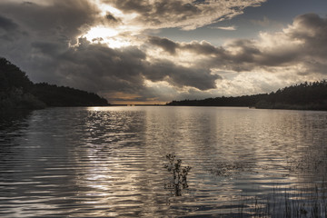 sunset in the Revenga reservoir, Segovia, Spain. Golden and silver tones with reflections in the water. Calm scene.
