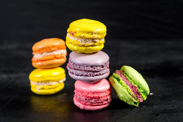 Many colored macaroons on black background