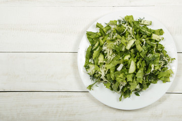 Vegetable salad with fresh vegetables and arugula on a wooden table. Salad with green fresh vegetables in a glass bowl. Vegetarian food salad. The concept of a healthy diet