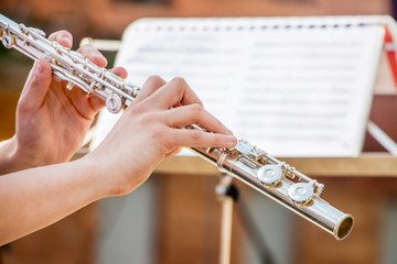 The girl plays the flute. Flute in the hands of the musician during the performance of the musical...