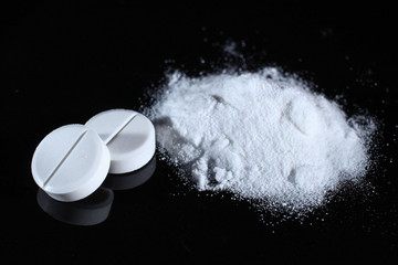 Pills and powder on a dark background