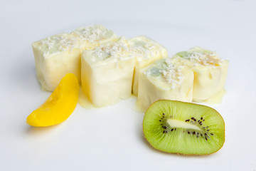 dessert of six rolls of cottage cheese near to pieces of pineapple and kiwi