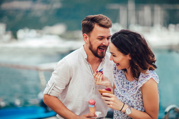 Happy couple having date and eating ice cream on vacation. Sea background.