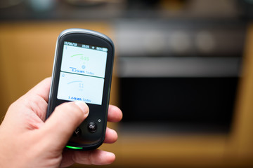 Man holding a Domestic Energy Smart Meter unit in a kitchen, Displaying Energy Usage in Real Time