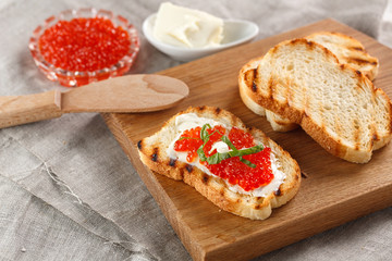 toasts with butter and Red caviar on a wooden cutting Board