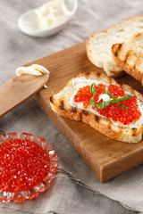 toasts with butter and Red caviar on a wooden cutting Board