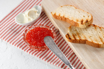 toasts with butter and Red caviar on a wooden cutting Board