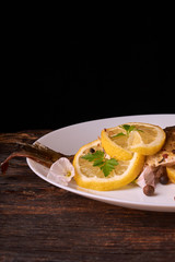 Grilled fish with herbs and lemon on wooden background. Mediterranean luxurious seafood concept