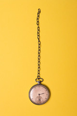 Old pocket watch on yellow background 