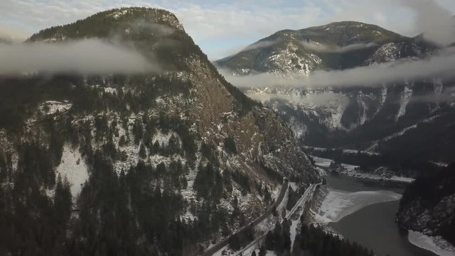 Aerial 4k footage of a river passing in the valley between the mountains in the Canadian Winter Landscape. Taken near Hope, British Columbia, Canada.
