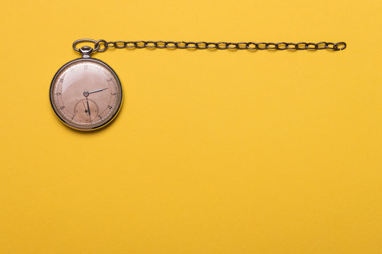 Old pocket watch on yellow background 