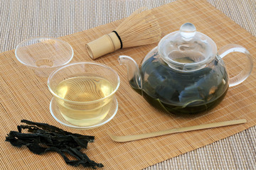Japanese sencha wakame seaweed green tea with glass teapot and cup, stirrer and whisk on bamboo...