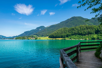 Steg entlang am See in Österreich welcher Wolfgangsee genannt wird mit Berge im Hintergrund und Wolken am Himmel