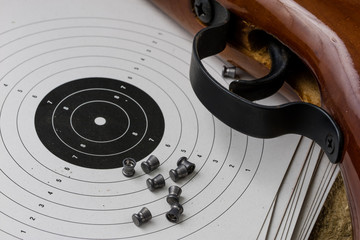 Shooting and pneumatic weapon. Shield and hits with lead bullets on a wooden table.