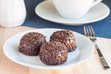 Swedish sweets Arrack balls, made from cookie crumbs, cocoa, butter and coconut wine Arrack flavour, on wooden table with a cup of tea, horizontal