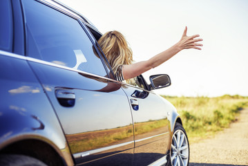 An attractive woman in a car holds a car key in her hand.