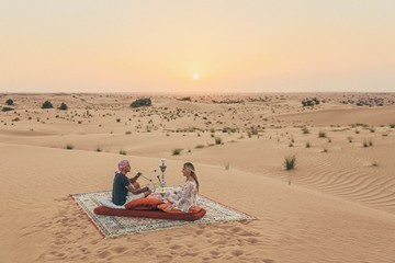 Romantic couple seating on a carpet in the Emirates desert  © xavier
