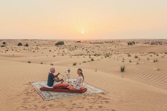 Romantic Couple Seating On A Carpet In The Emirates Desert 