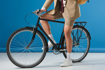 Fototapeta na wymiar cropped shot of man in shorts sitting on bicycle on blue