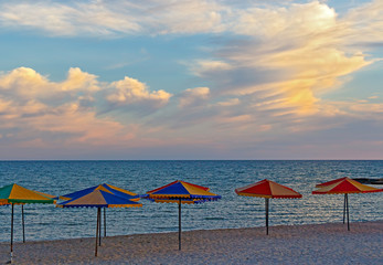 Sea beach with umbrellas against the sky before sunset
