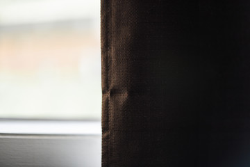 A brown curtain in front of day lit window.