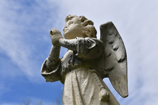 Weathered sandstone sculpture of a praying angel on a cemetery of Montreal-Canada