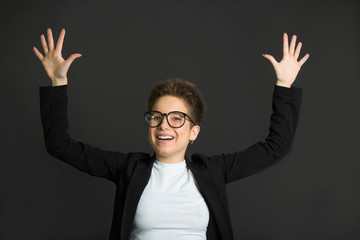 beautiful young girl with short hair, in a black suit and wearing glasses on a black background
