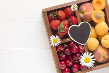 Strawberry, sweet cherry and apricots in a wooden box