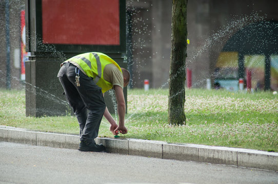 transportation company employee adjusting automatic sprinklers on tramway line