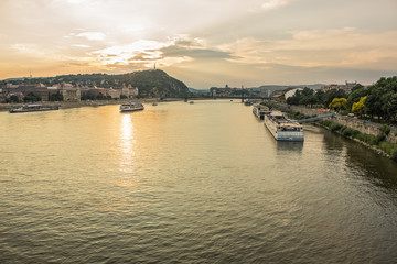 Obraz premium evening urban city scape of waterfront with river and ships in sunset time with sun rays and soft colors