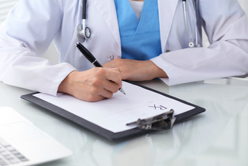 Doctor woman filling up prescription, close-up of hands. Physician at work. Medicine and healthcare concept