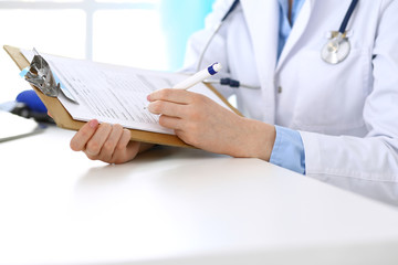 Female doctor filling up medical form on clipboard closeup. Healthcare, insurance and medicine concept
