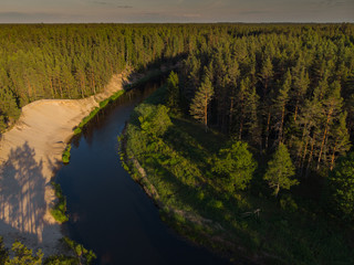 top view to bending river in green forest  on sunset