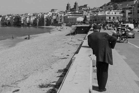 CEFALU, PALERMO, SICILY. April 2017: black and white shoot of old time Sicilian rural city. Old man wearing typical coppola hat, and fisherman houses facing the sea.