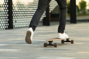 Man skateboarder riding longboard in the city, outdoors, cropped image. Leisure, healthy lifestyle, extreme sports concept