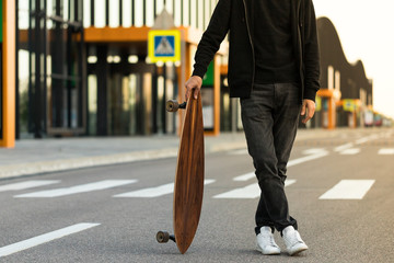 Man hipster standing with skateboard or longboard outdoors, cropped image. Leisure, healthy...