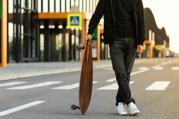Man hipster standing with skateboard or longboard outdoors, cropped image. Leisure, healthy lifestyle, extreme sports  © DimaBerlin