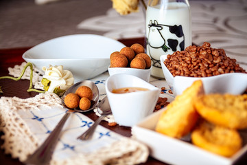 Tray with continental breakfast on hotel bed made of cereals, Cinnamon Balls, chocolate, cakes and a bowl with spoon. Breakfast in bed. Front view
