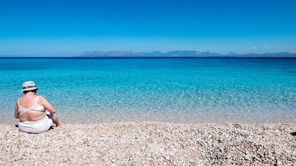 Fototapeta na wymiar White pebbles beach with clear and transparent turquoise water. Mediterranean Sea at San Vito Lo Capo, the 