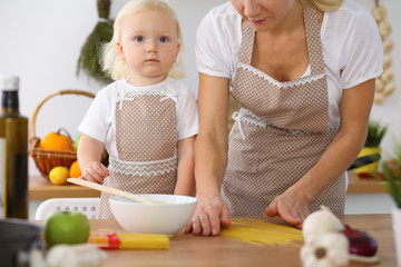Mother and little daughter  cooking in the kitchen. Spending time all together or happy family concept