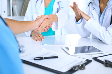 Two doctors shaking hands to each other at meeting. Teamwork and agreement in medicine