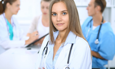 Happy doctor woman  with medical staff at the background in hospital office